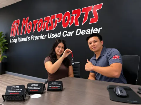 Cliente recibiendo las llaves de su auto en el escritorio de ventas de AR Motorsports en Bay Shore, NY