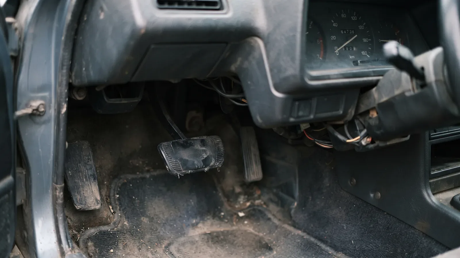 Close-up of a worn brake pedal with the rubber rubbed smooth, next to a dashboard showing low mileage